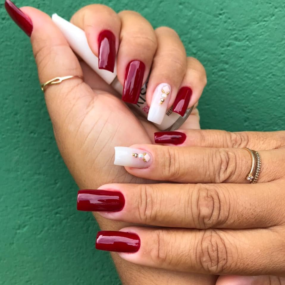 Unhas vermelhas com detalhes em branco e pedras douradas