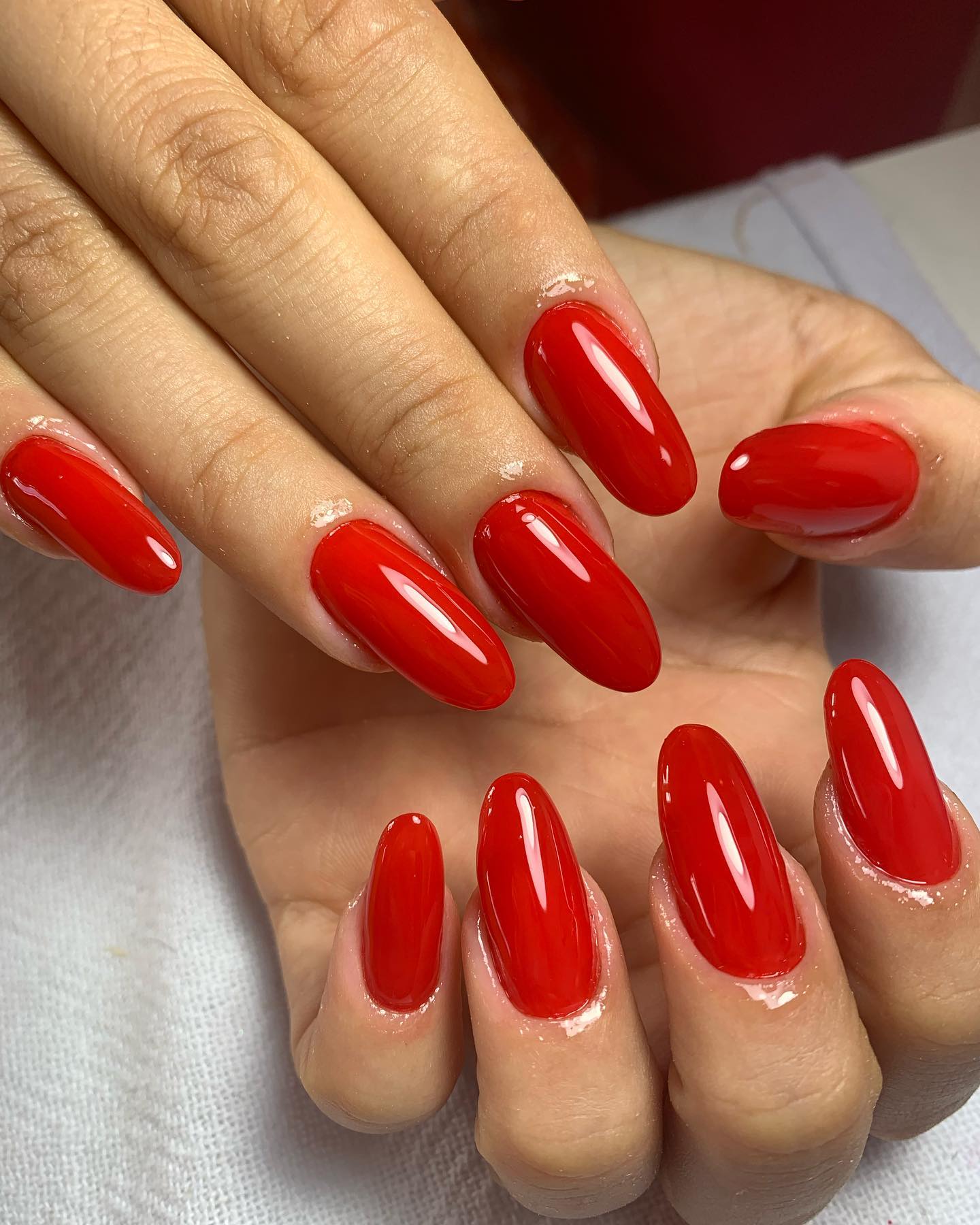 Unhas vermelhas brilhantes em formato oval