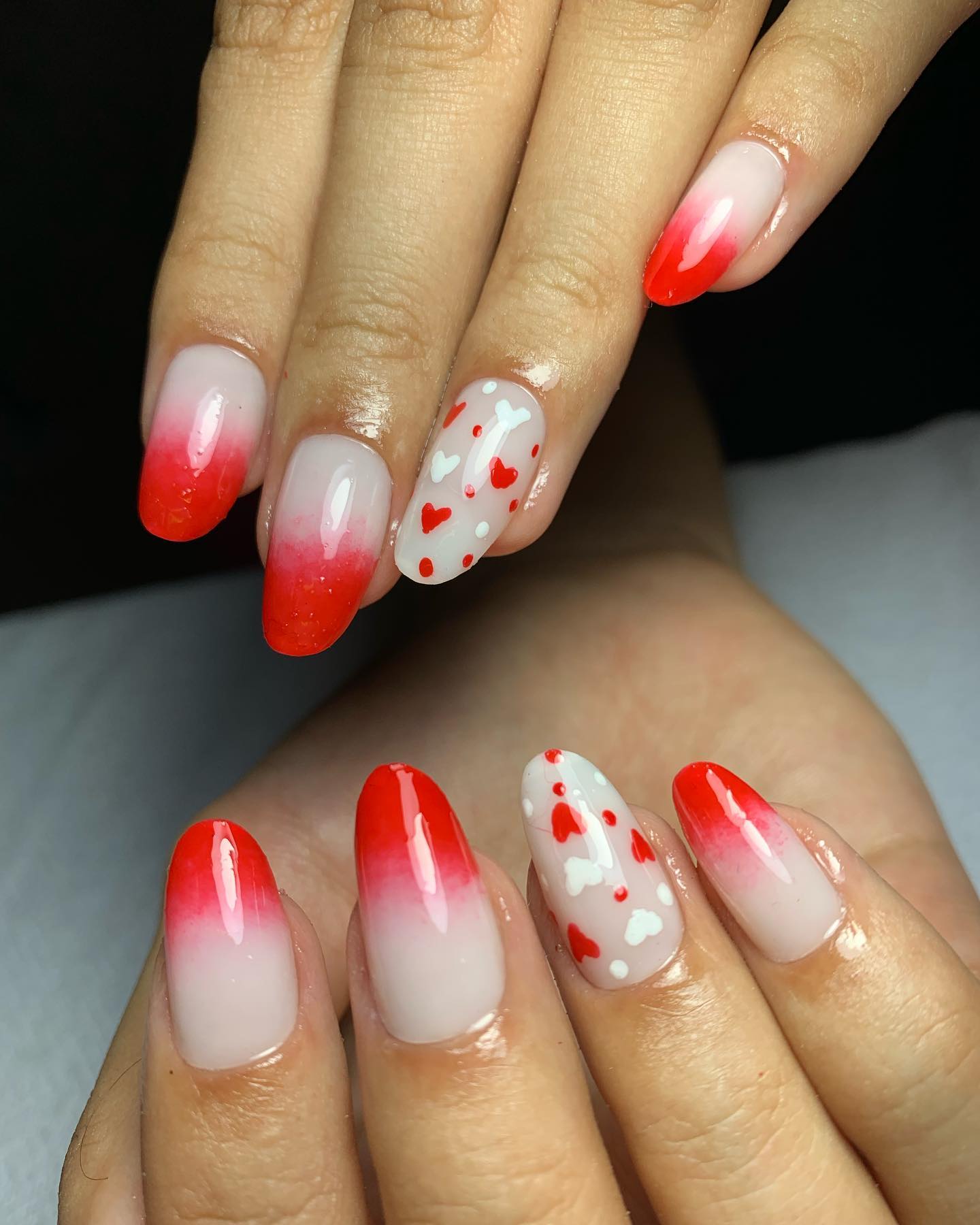 Unhas com degradê branco-vermelho e detalhes de corações